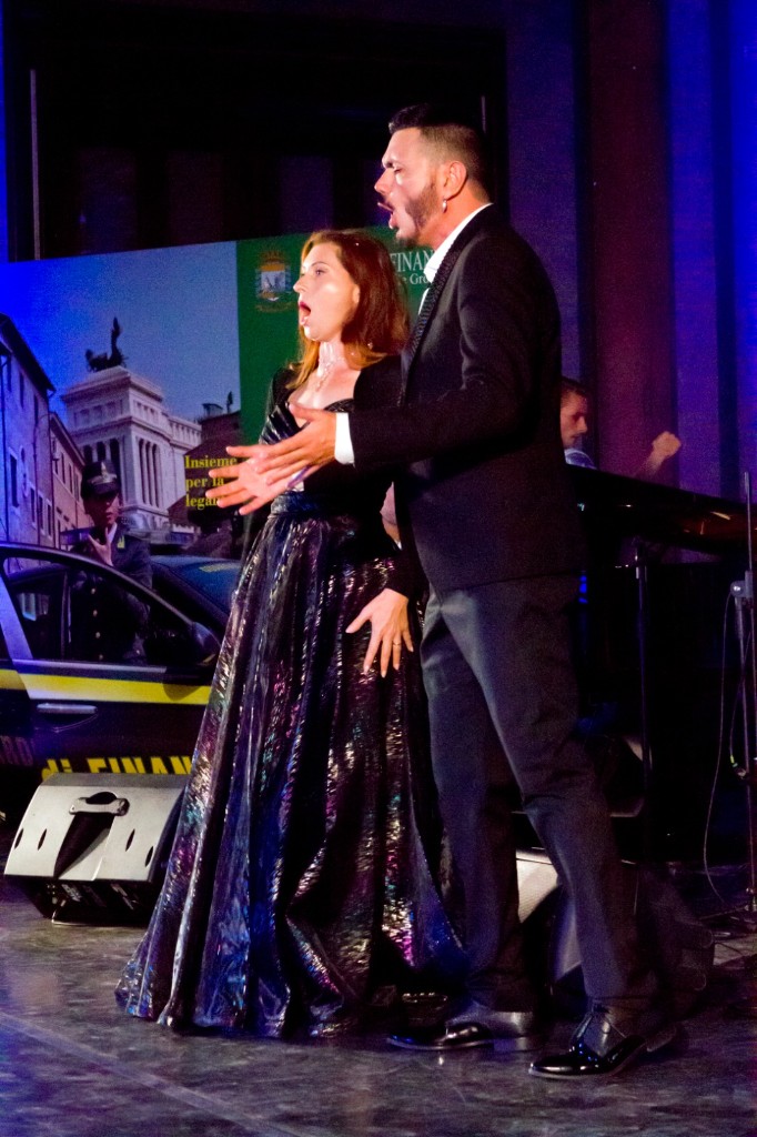 Soprano e tenore in scena durante un evento serale con allestimento “Insieme per la legalità”.